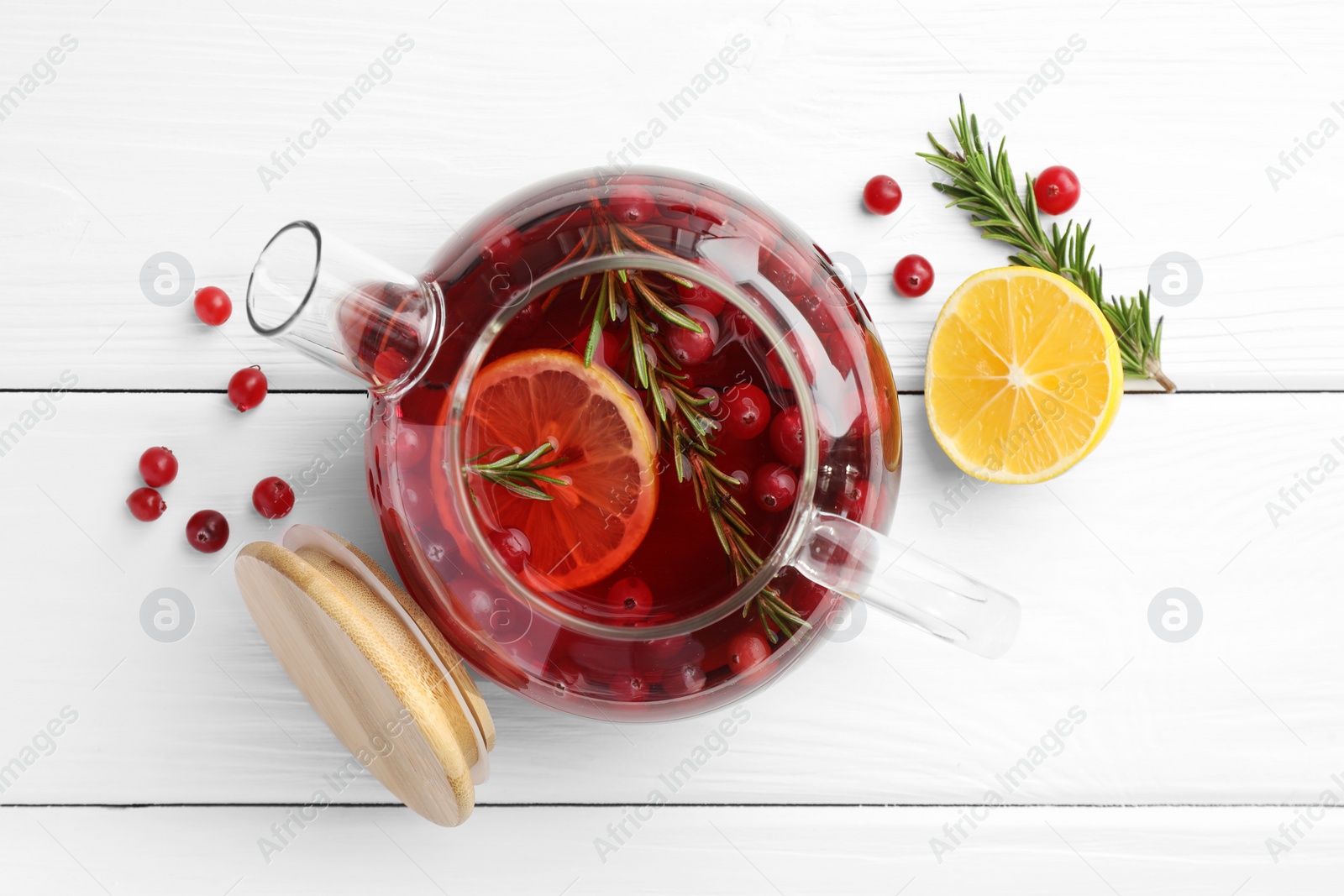 Photo of Tasty hot cranberry tea with lemon, rosemary and fresh berries on white wooden table