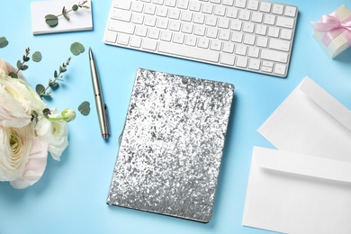 Composition with glittering notebook, keyboard and spring flowers on color background