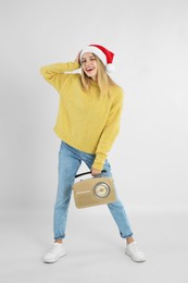 Photo of Happy woman with vintage radio on light grey background. Christmas music