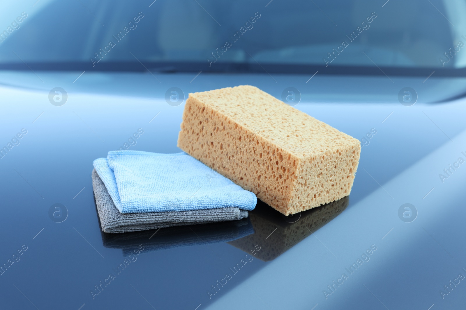 Photo of Sponge and rags on car hood. Cleaning products