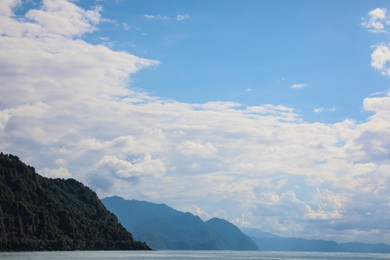 Picturesque view of mountains and sea under beautiful blue sky with fluffy clouds