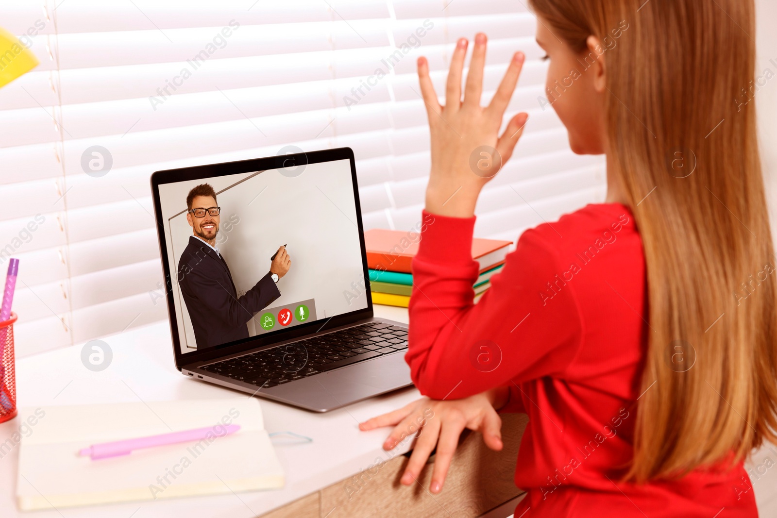 Image of E-learning. Little girl raising her hand to answer during online lesson at table indoors