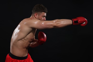 Man in boxing gloves fighting on black background