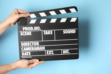 Photo of Woman holding clapperboard on color background, closeup. Cinema production