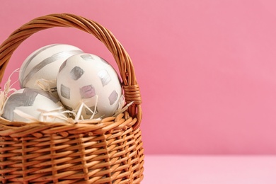 Basket of Easter eggs on table against color background, closeup. Space for text