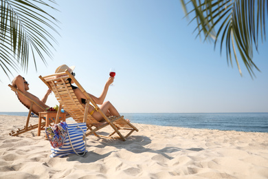 Couple with wine on sunny beach at resort