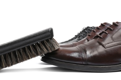 Photo of Stylish men's shoes and cleaning brush on white background, closeup