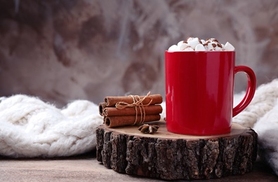 Composition of tasty cocoa with marshmallows in cup on wooden table. Space for text