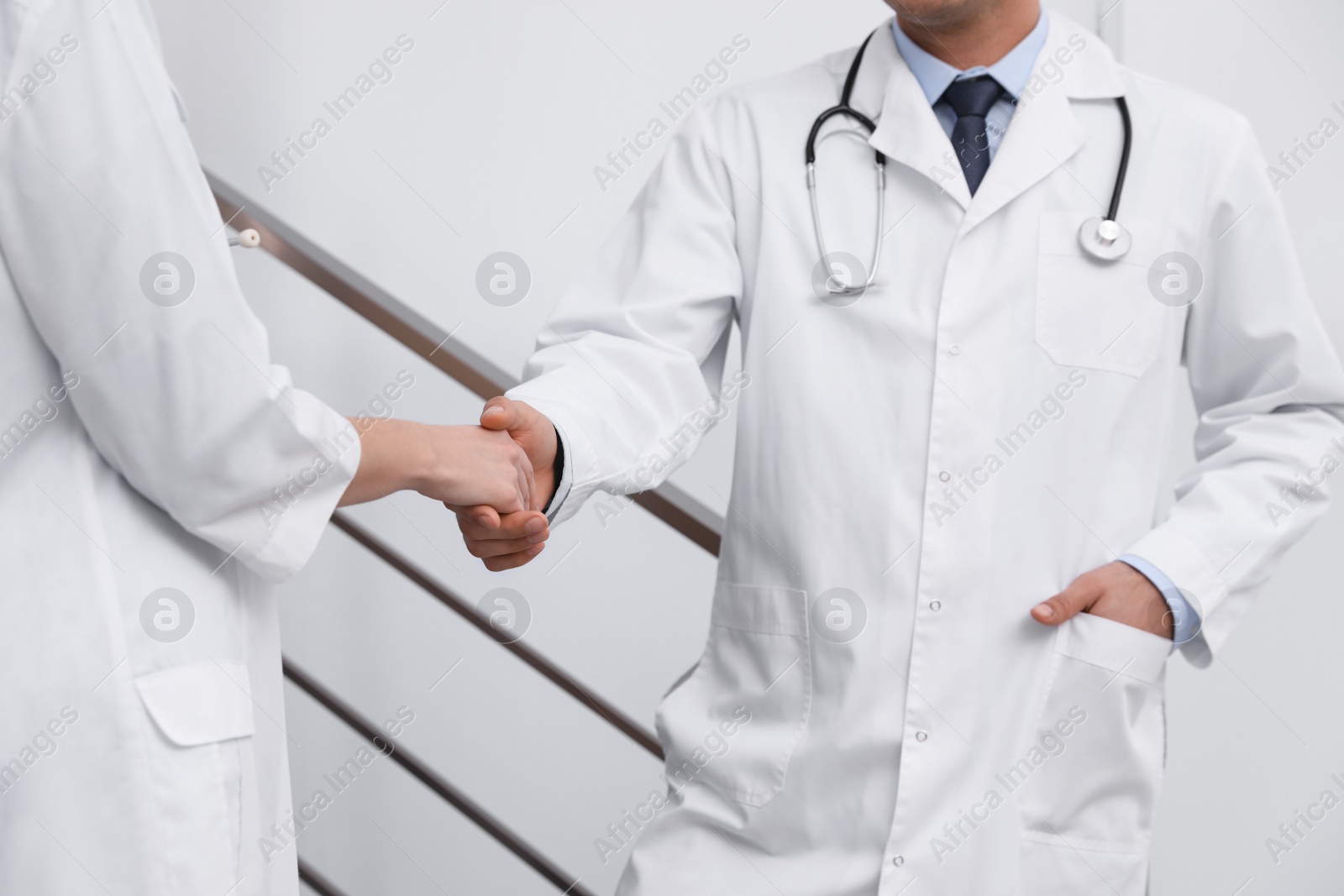Photo of Doctors greeting with handshake in clinic, closeup