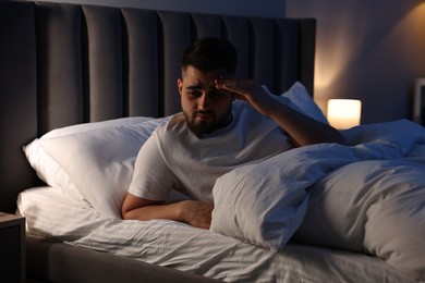 Photo of Frustrated man suffering from insomnia in bed