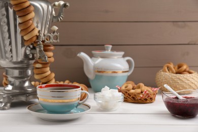 Photo of Cup of tea and delicious ring shaped Sushki (dry bagels) on white wooden table, space for text