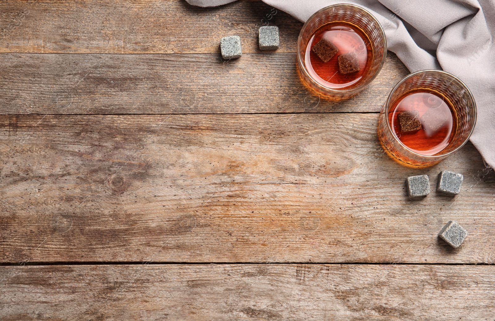 Photo of Glasses with liquor and whiskey stones on wooden background, top view