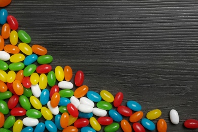 Top view of delicious jelly beans on wooden background. Space for text