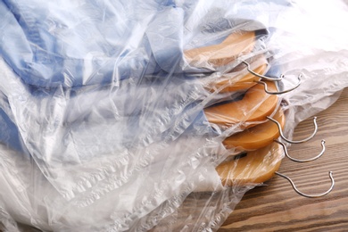 Photo of Clean clothes after dry-cleaning on table