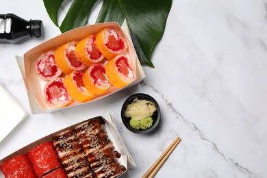 Photo of Food delivery. Delicious sushi rolls served on white marble table, flat lay with space for text