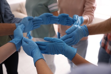 Photo of People in blue medical gloves showing circle with hands on light background, closeup