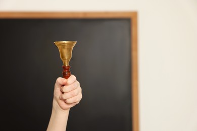 Photo of Boy ringing school bell in classroom, closeup. Space for text
