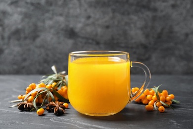 Sea buckthorn tea and fresh berries on grey table