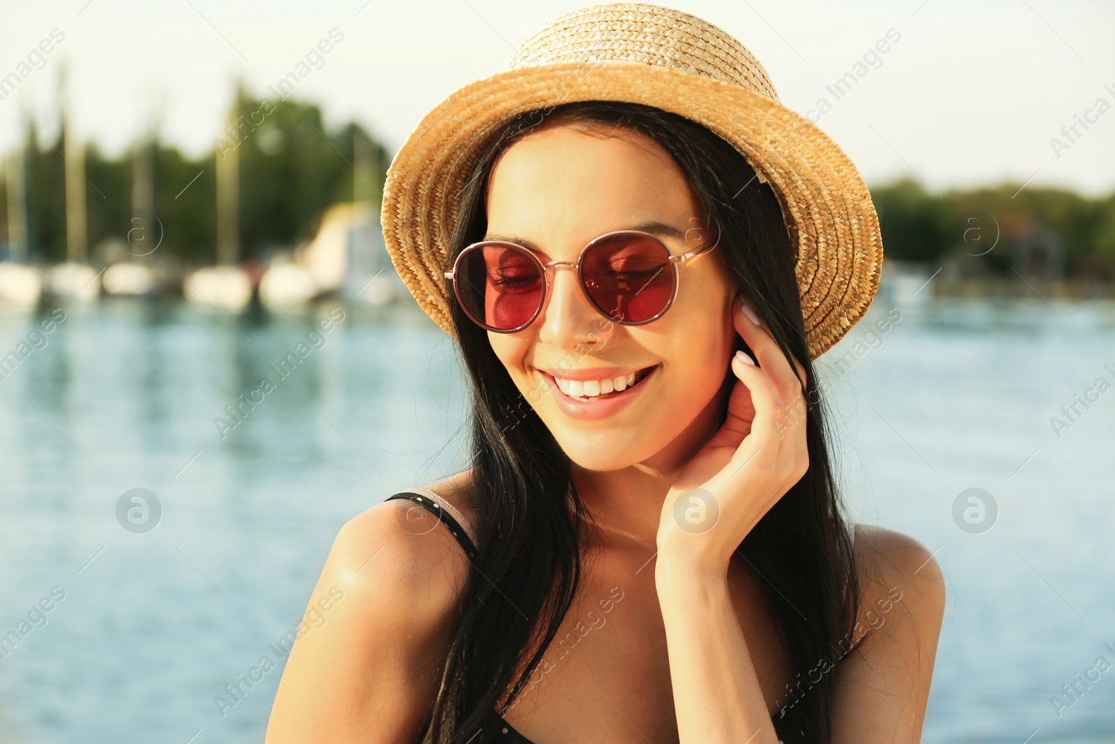 Photo of Beautiful young woman wearing stylish sunglasses near river