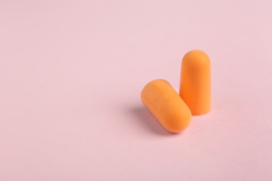 Photo of Pair of orange ear plugs on pink background. Space for text