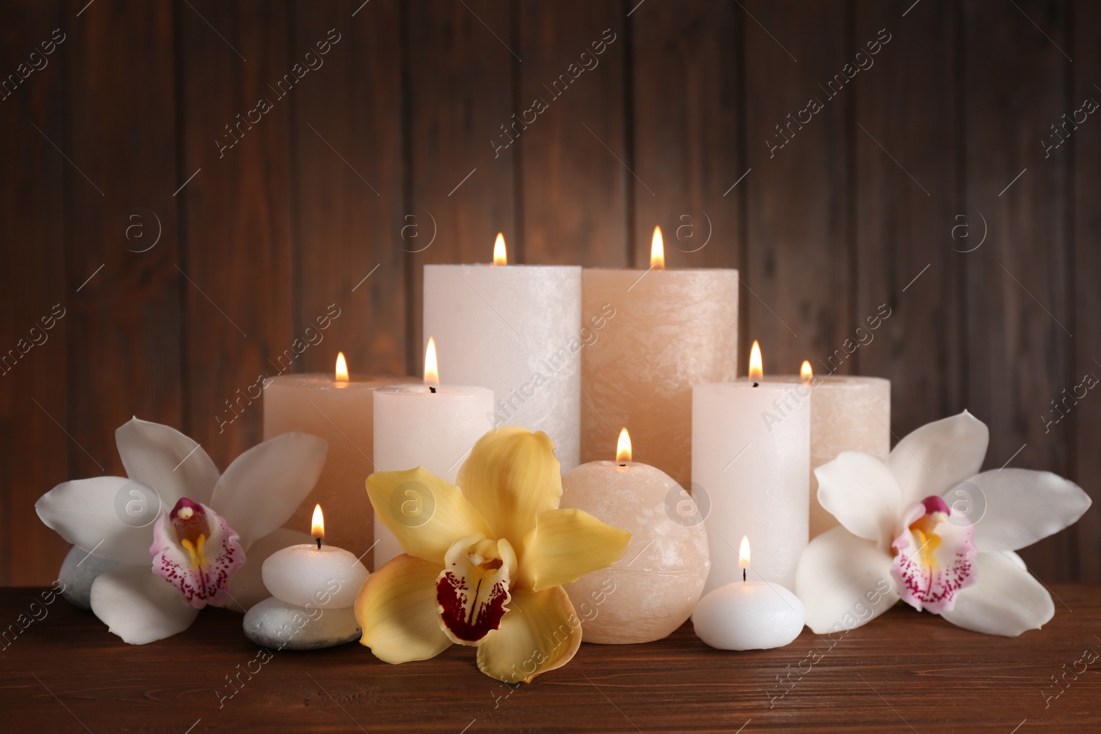 Photo of Beautiful composition with candles and flowers on table against wooden background