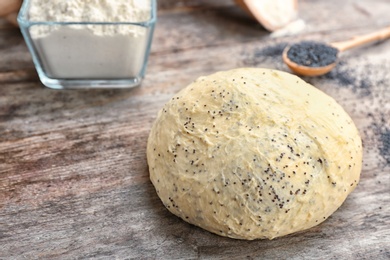 Photo of Raw dough with poppy seeds on wooden table