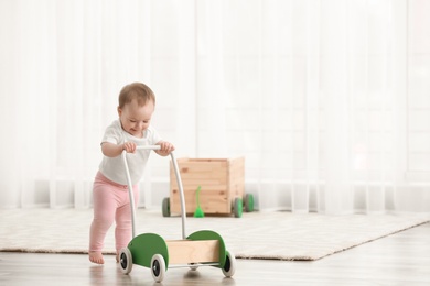 Cute baby with toy walker at home