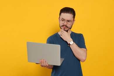 Photo of Pensive man using laptop on orange background