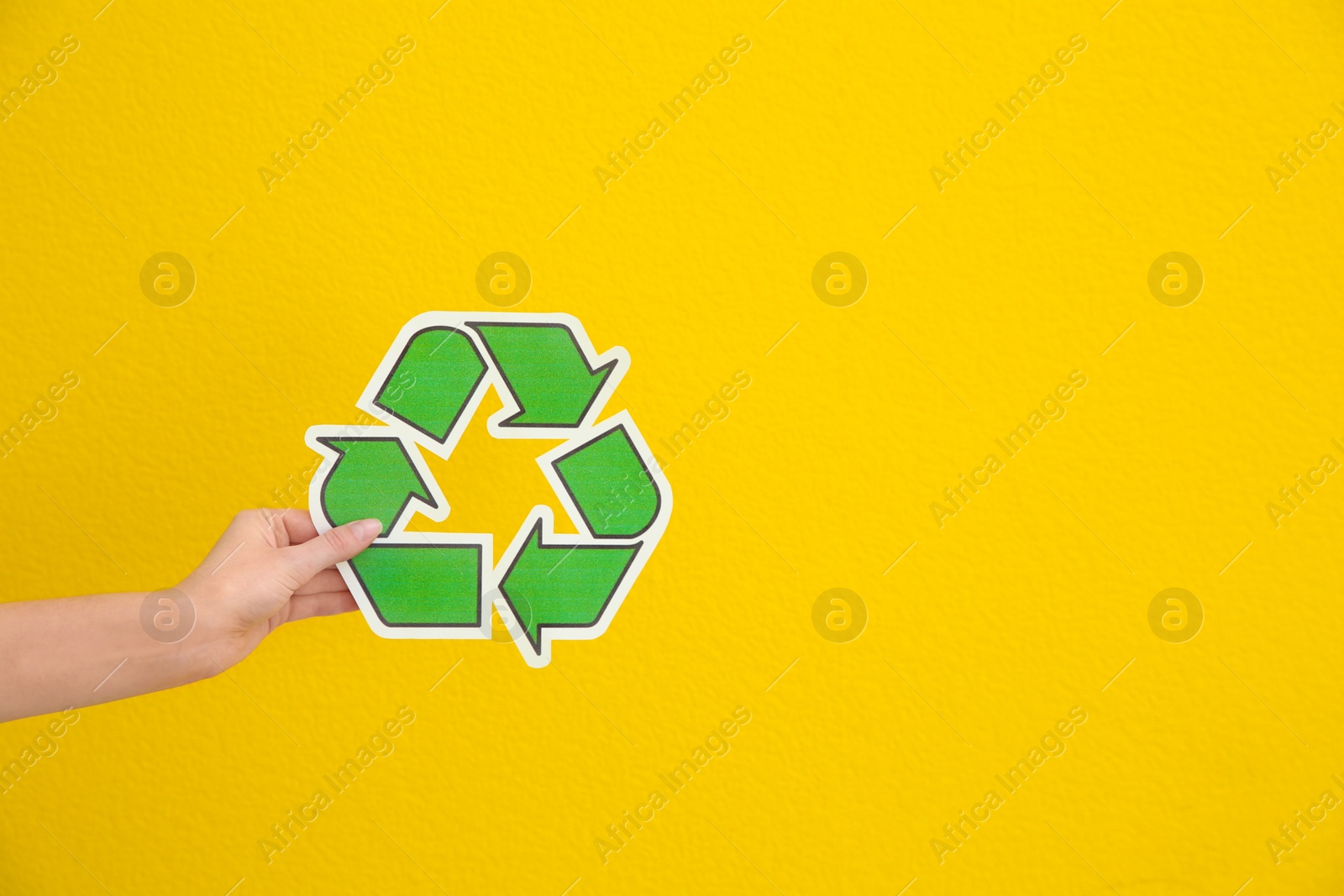 Photo of Woman holding recycling symbol on color background, closeup. Space for text