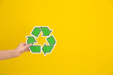 Woman holding recycling symbol on color background, closeup. Space for text