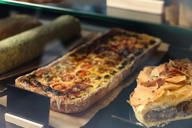 Photo of Delicious cheese quiche on counter in bakery shop, closeup. Space for text