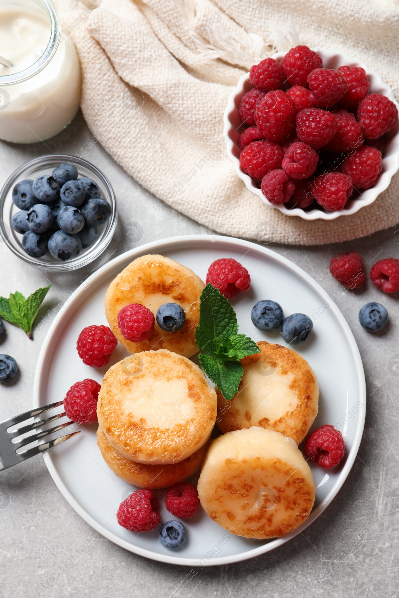 Photo of Delicious cottage cheese pancakes with berries on light table, flat lay