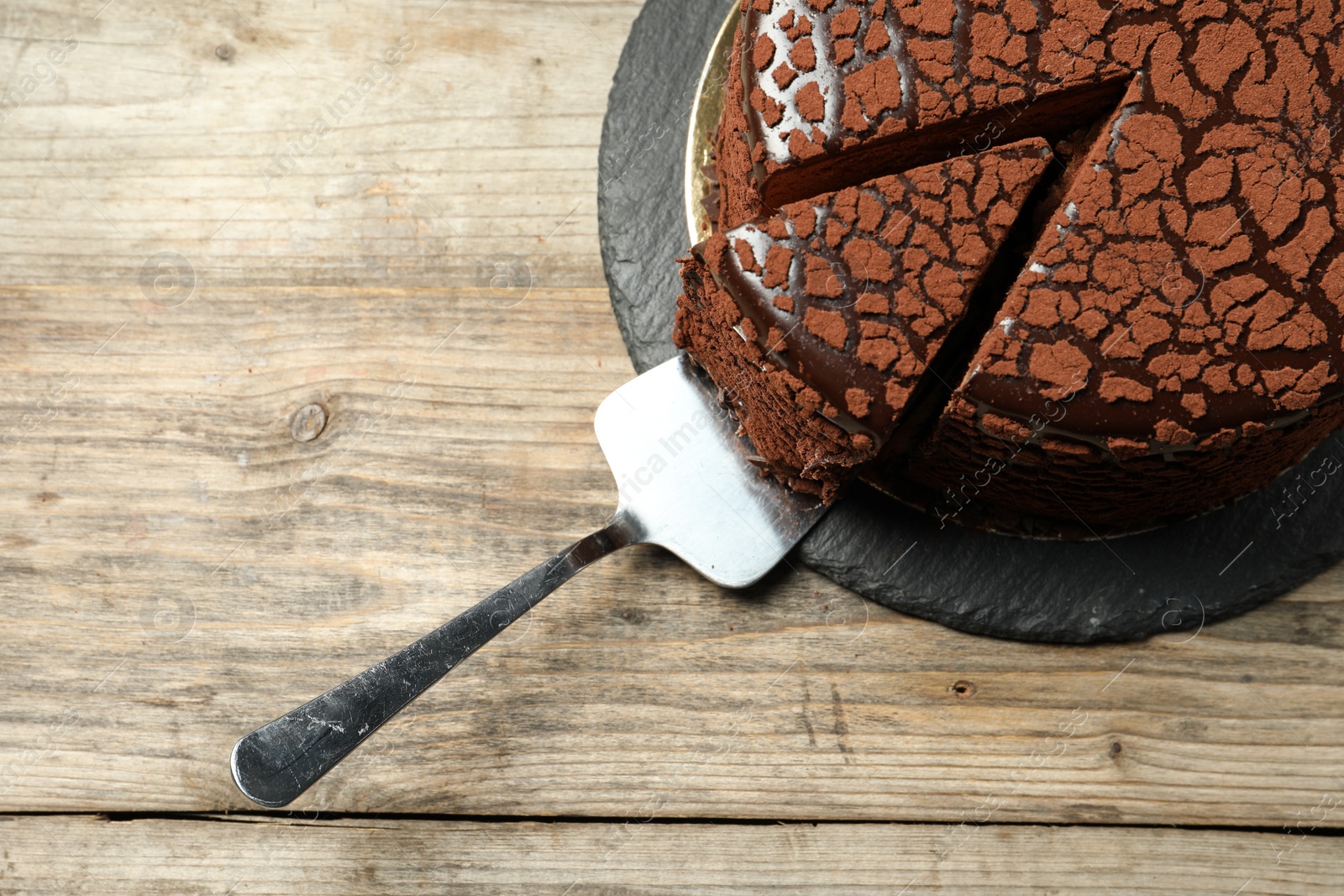 Photo of Delicious chocolate truffle cake and server on wooden table, top view. Space for text