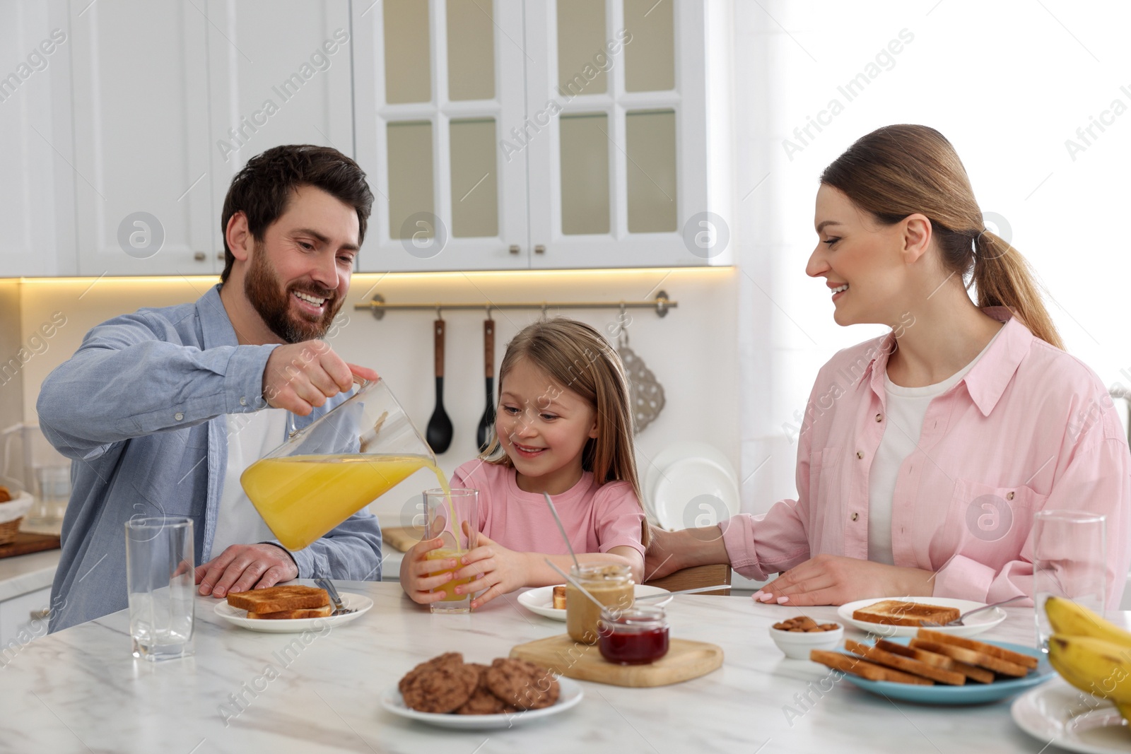 Photo of Happy family having breakfast at table in kitchen