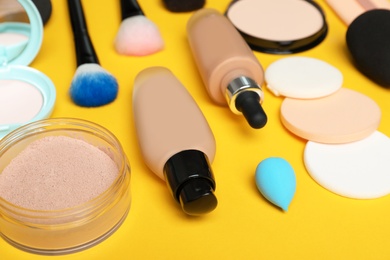 Photo of Composition with skin foundation, powder and beauty accessories on color background