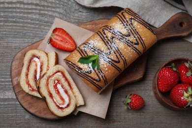 Photo of Tasty cake roll with strawberry jam and cream on wooden table, flat lay