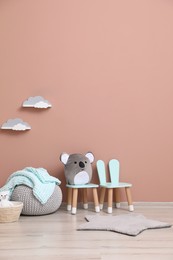 Photo of Child's toys, pouf and chairs near pink wall indoors. Interior design