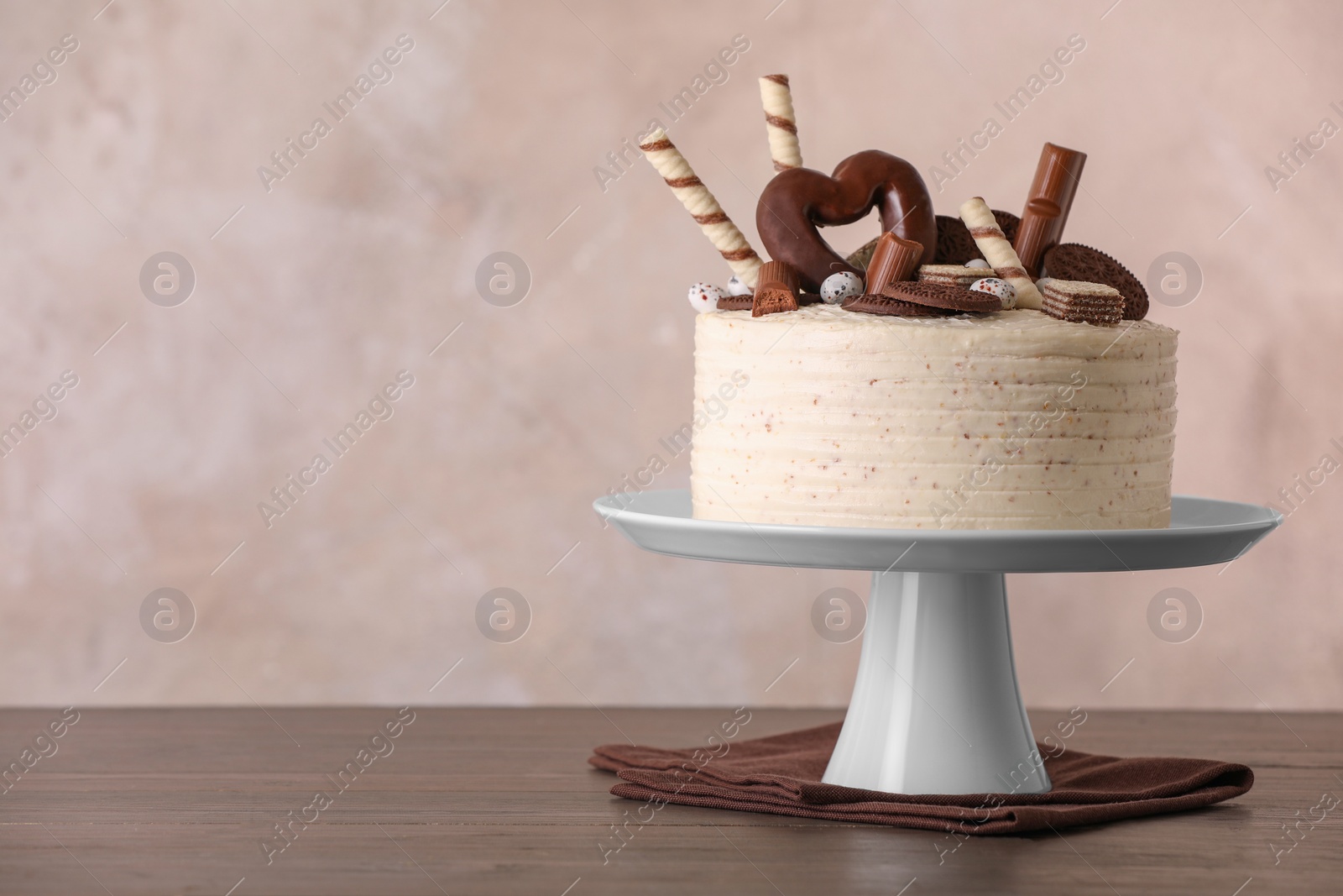 Photo of Delicious cake decorated with sweets on wooden table, space for text