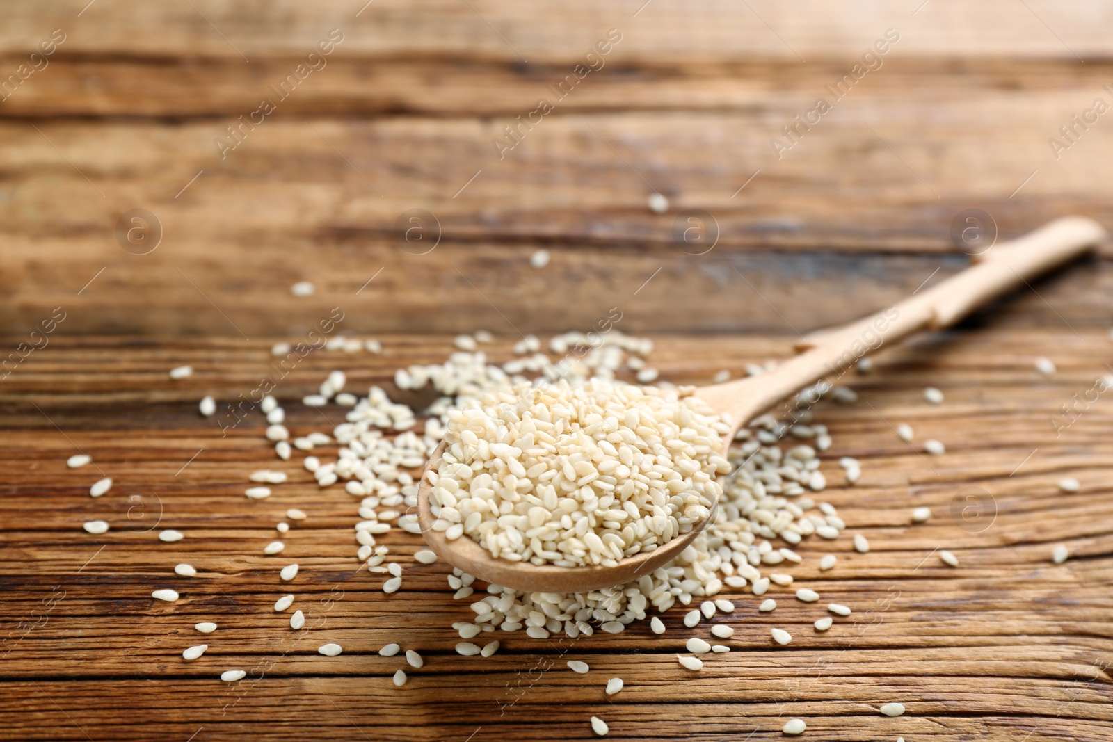 Photo of White sesame seeds on wooden table, closeup