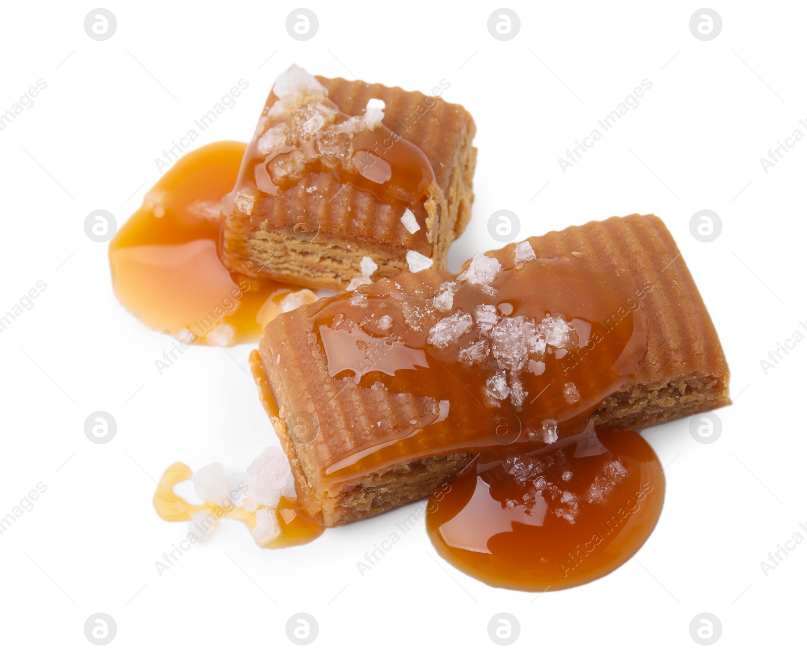 Photo of Yummy caramel candies and sea salt isolated on white