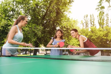 Photo of Happy family with child playing ping pong in park
