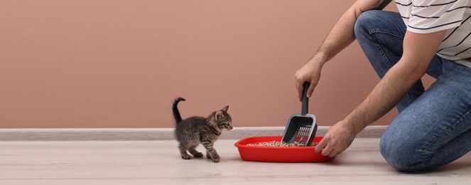 Image of Man cleaning cat litter tray at home, closeup. Banner design with space for text