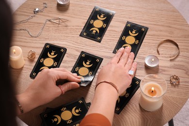 Soothsayer predicting future with tarot cards at wooden table, closeup
