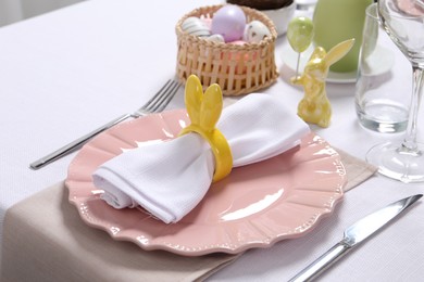 Photo of Festive table setting with napkin ring in shape of bunny ears, closeup. Easter celebration