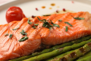 Photo of Tasty grilled salmon with asparagus and spices on plate, closeup