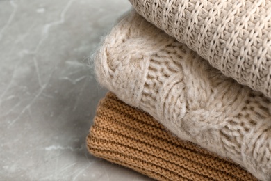 Photo of Stack of folded knitted sweaters on table, closeup. Space for text