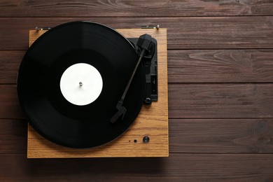 Photo of Turntable with vinyl record on wooden background, top view