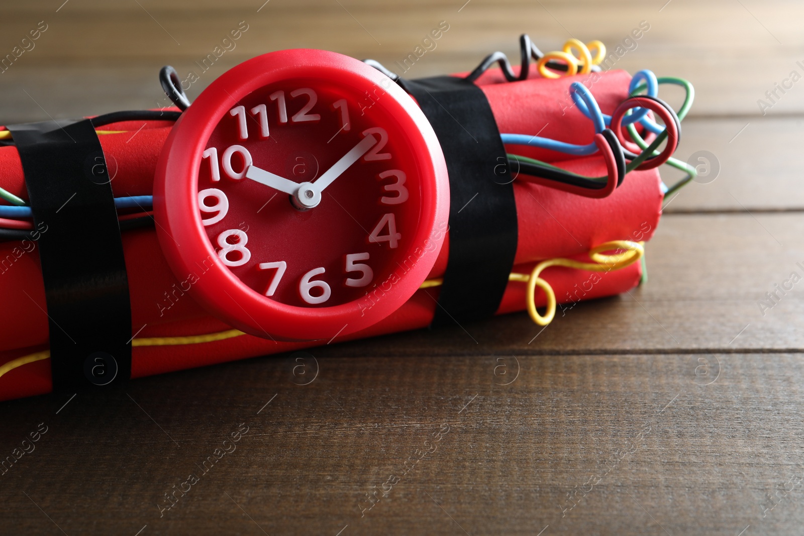 Photo of Dynamite time bomb on wooden table, closeup