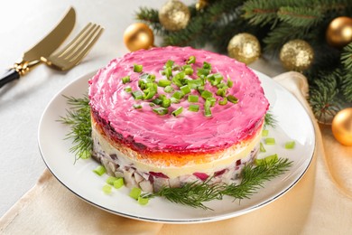Photo of Herring under fur coat salad and Christmas decor on light grey table. Traditional Russian dish