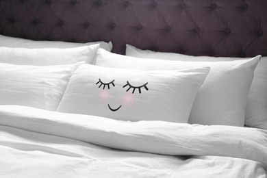 Image of Soft pillow with cute face on comfortable bed 